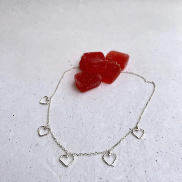 Handmade silver necklace with five small hearts hanging on a silver chain