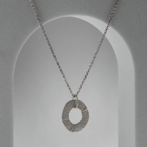 Kiwi pendant necklace in handmade hammered recycled sterling silver, featuring an irregular circular openwork design by Vasiliki Sountou Jewellery.